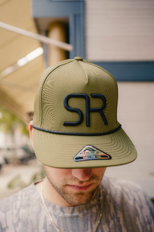 Person wearing a green cap with 'SR' logo, blurred background
